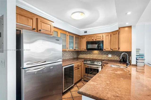a kitchen with stainless steel appliances granite countertop a refrigerator a stove and a sink with wooden floor