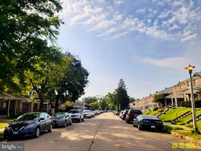 a view of road with card parked on side and retail shops