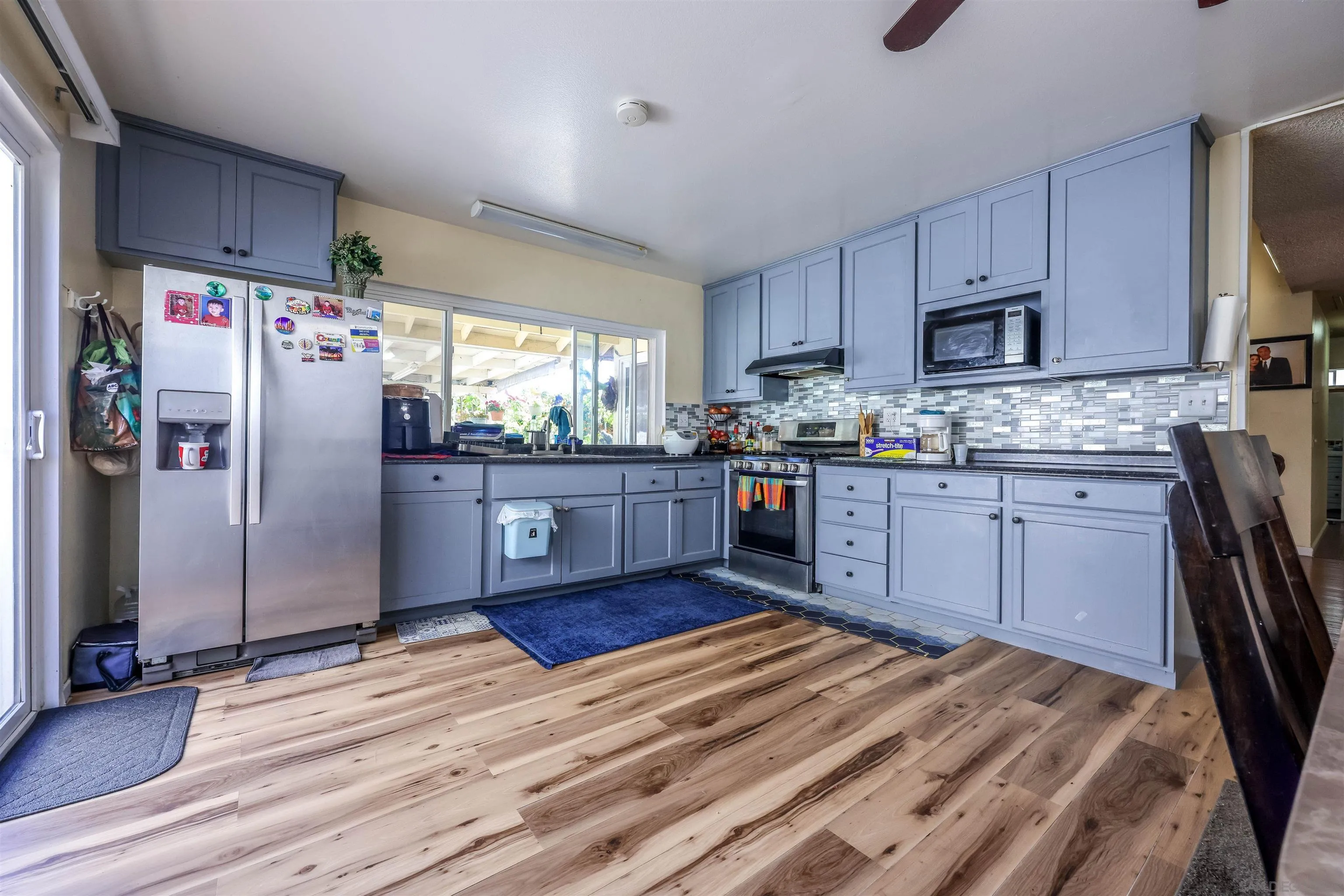 a kitchen with stainless steel appliances granite countertop a refrigerator a sink dishwasher a stove top oven a refrigerator and cabinets with wooden floor
