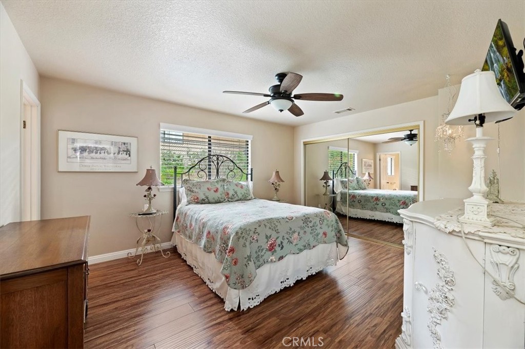 1168 North Crescent Ridge Road Fallbrook, CA 92028 - Photo 24 of 45 a spacious bedroom with a bed a chandelier and a dresser