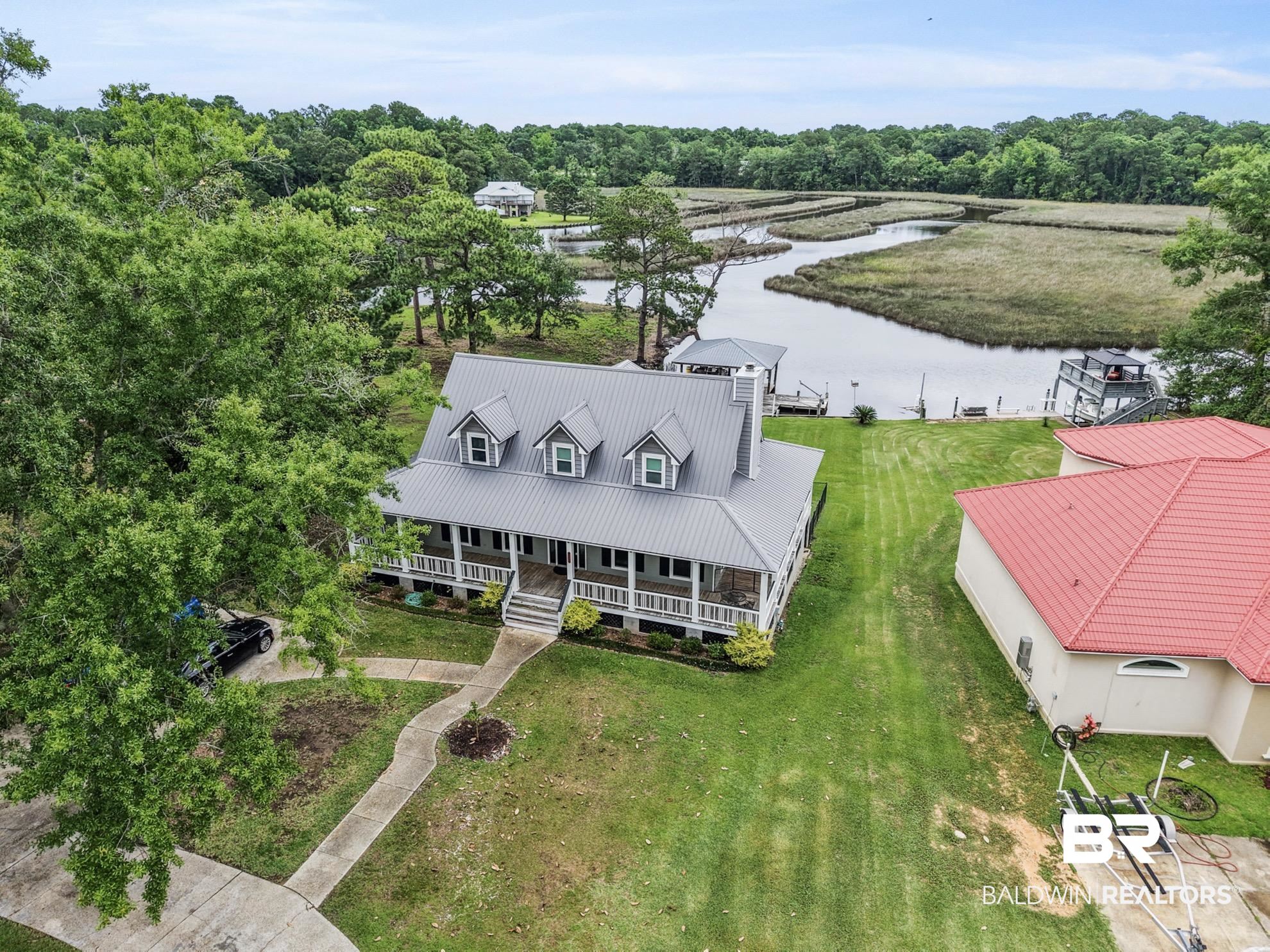 12171 Marguerite Drive Coden, AL 36523 - Photo 4 of 44 Waterfront property featuring a main residence with an expansive covered porch, metal roof, and multiple dormer windows