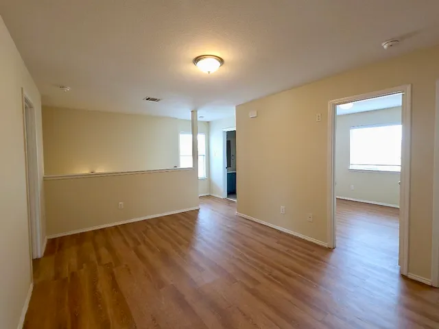 an empty room with wooden floor and windows