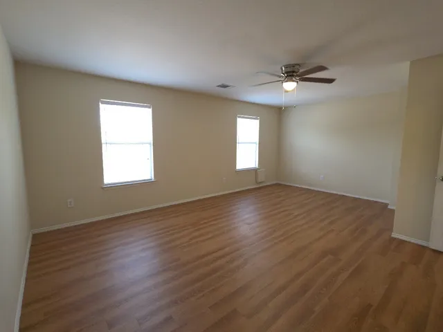 a view of empty room with wooden floor and fan