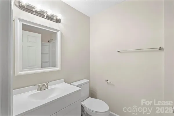 a bathroom with a toilet a sink a mirror and vanity