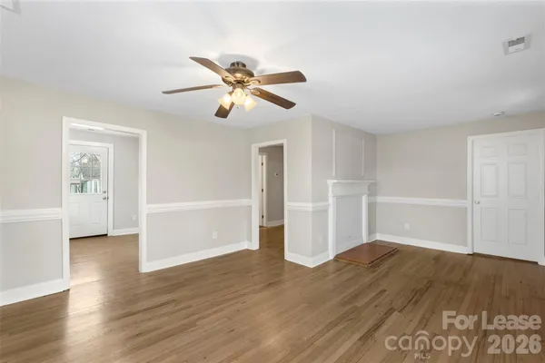 a view of empty room with wooden floor and ceiling fan