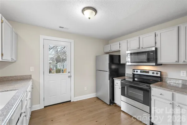 a kitchen with granite countertop a refrigerator stove and microwave