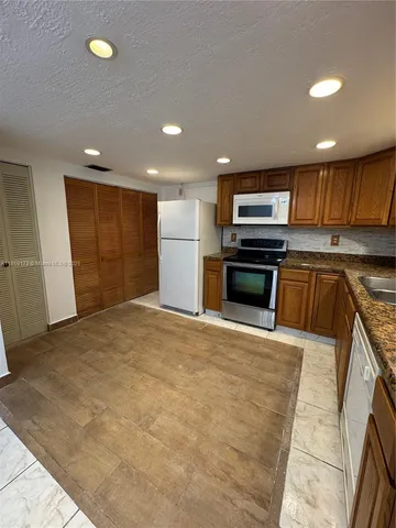 a kitchen with stainless steel appliances granite countertop a refrigerator a stove top oven a sink and dishwasher