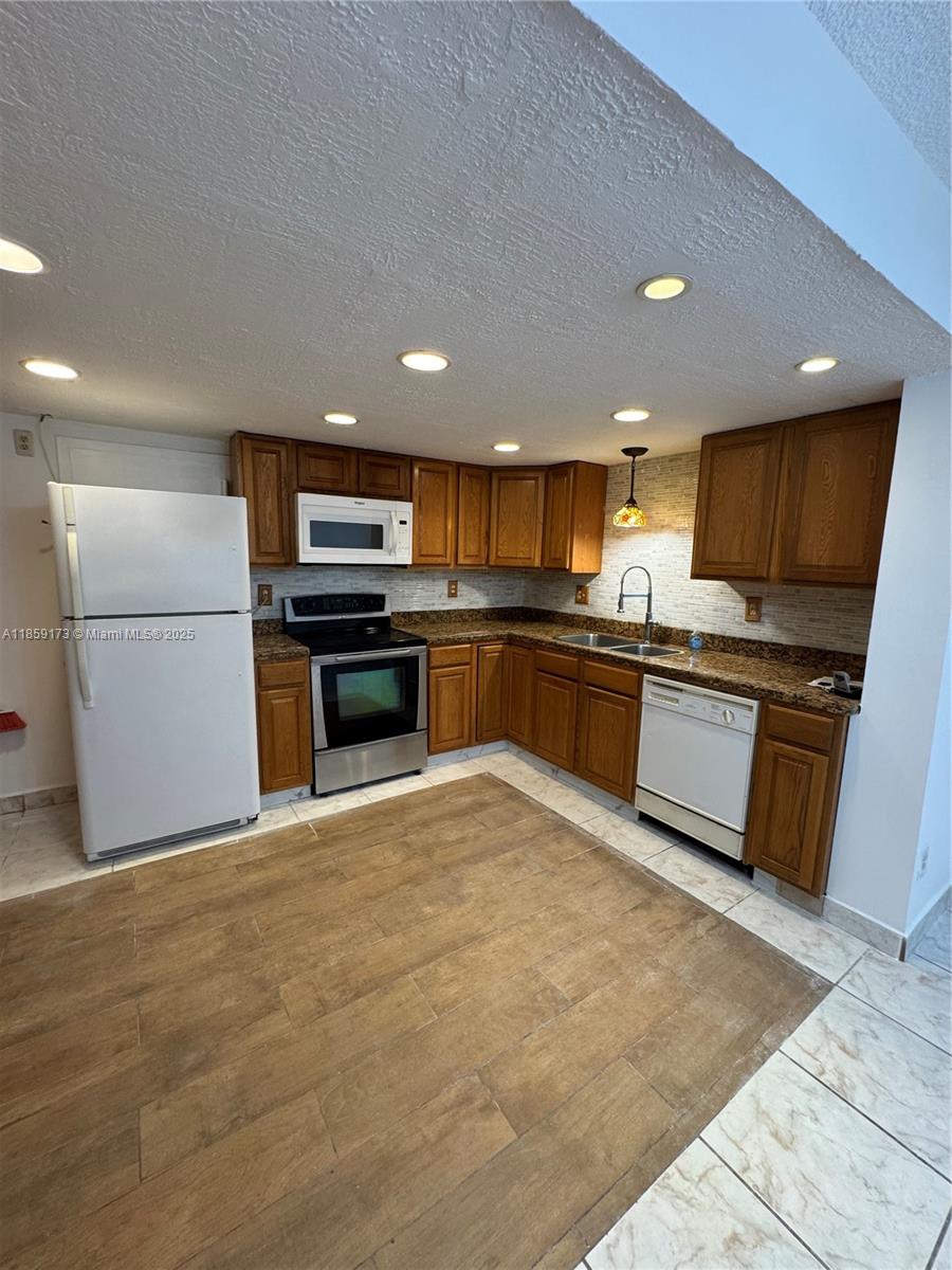 6841 Southwest 147th Avenue, Unit 1H Miami, FL 33193 - Photo 9 of 26 a kitchen with stainless steel appliances granite countertop a refrigerator a stove top oven a sink and dishwasher