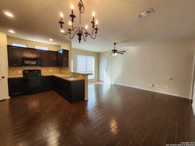 a large kitchen with stainless steel appliances a large counter top a stove and a wooden floor