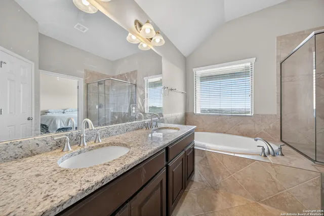a bathroom with a granite countertop bathtub a sink and a mirror