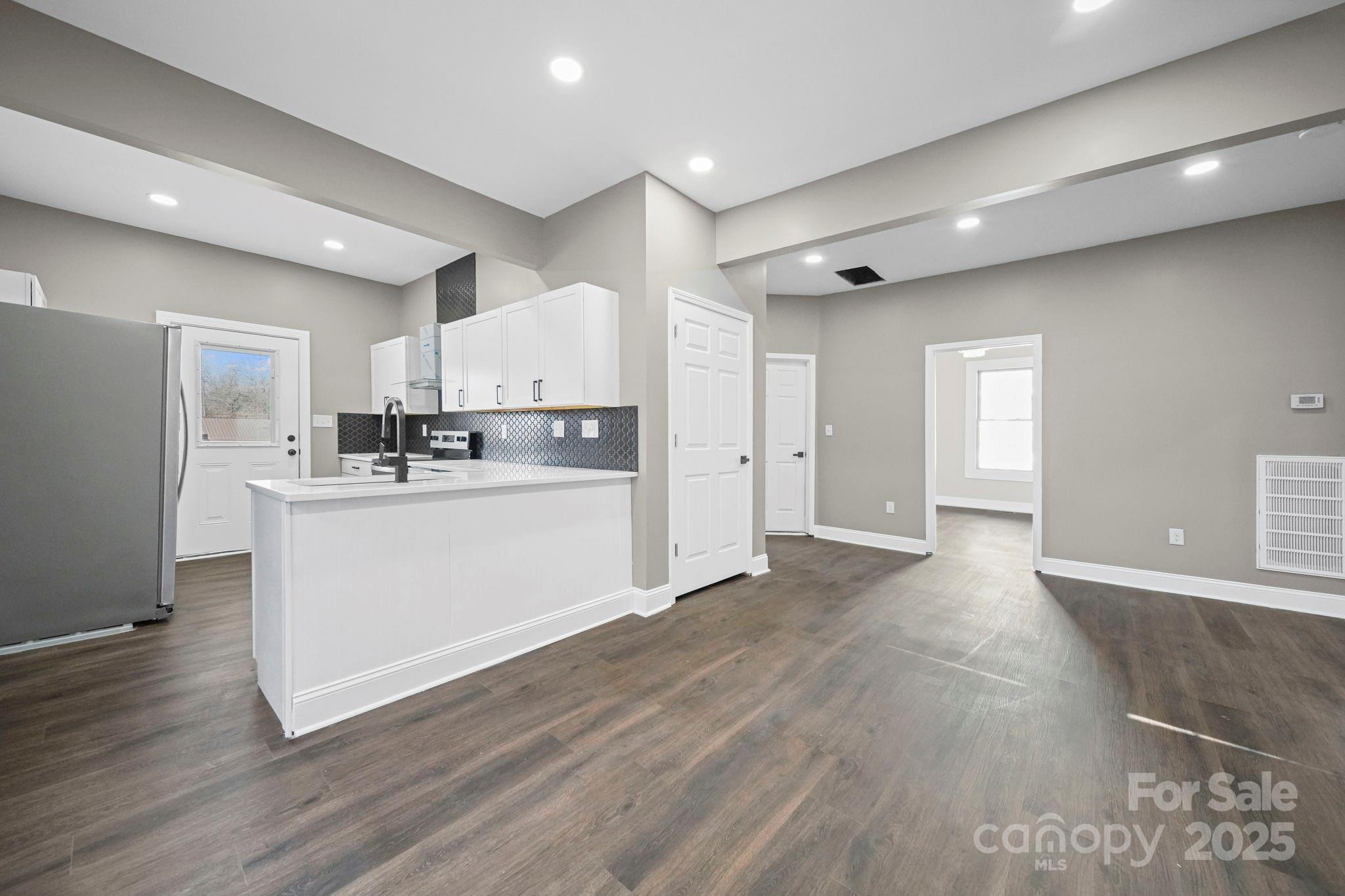 113 7th Street Spencer, NC 28159 - Photo 14 of 44 a large white kitchen with kitchen island a sink wooden floor and stainless steel appliances