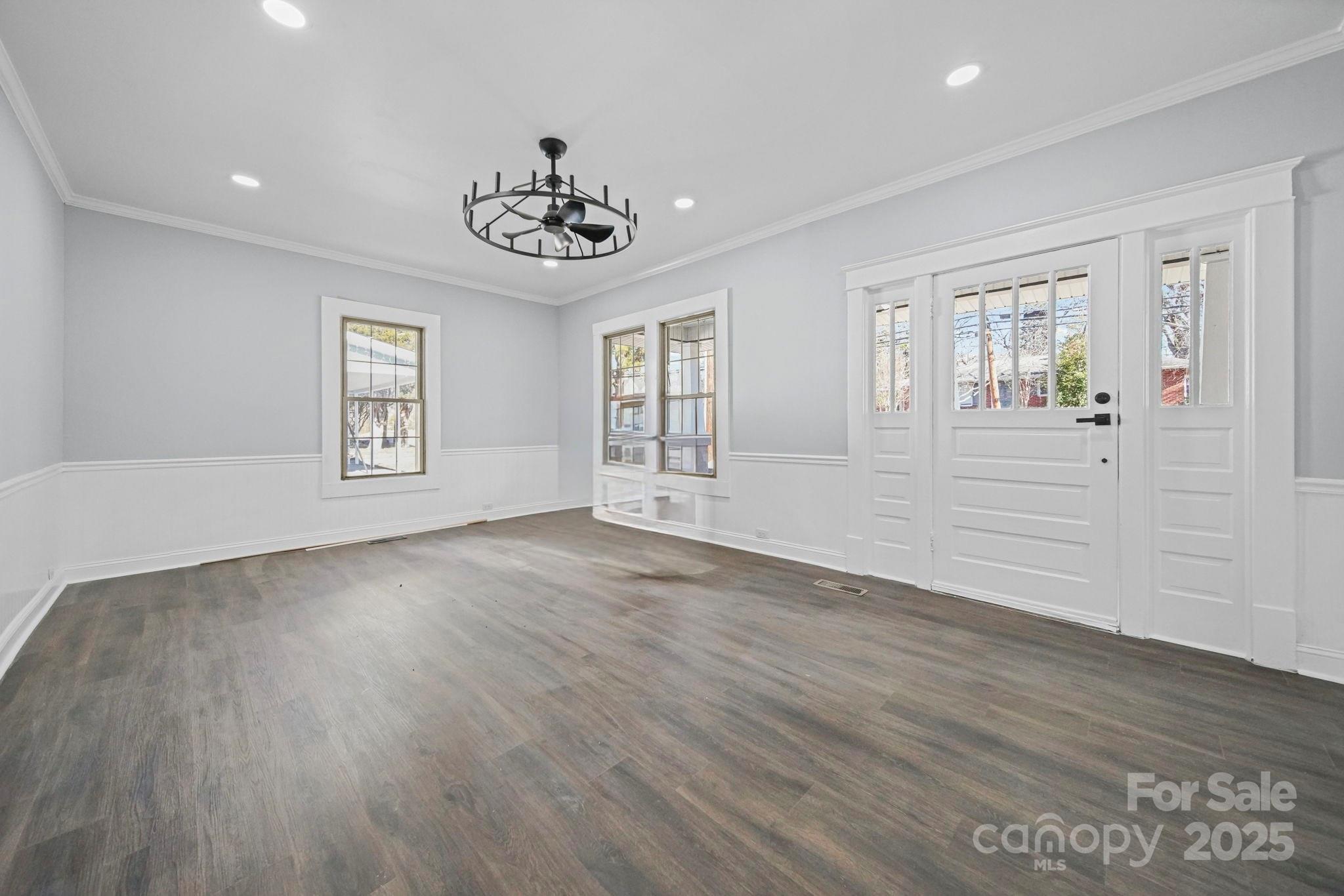 113 7th Street Spencer, NC 28159 - Photo 15 of 44 an empty room with wooden floor chandelier and windows