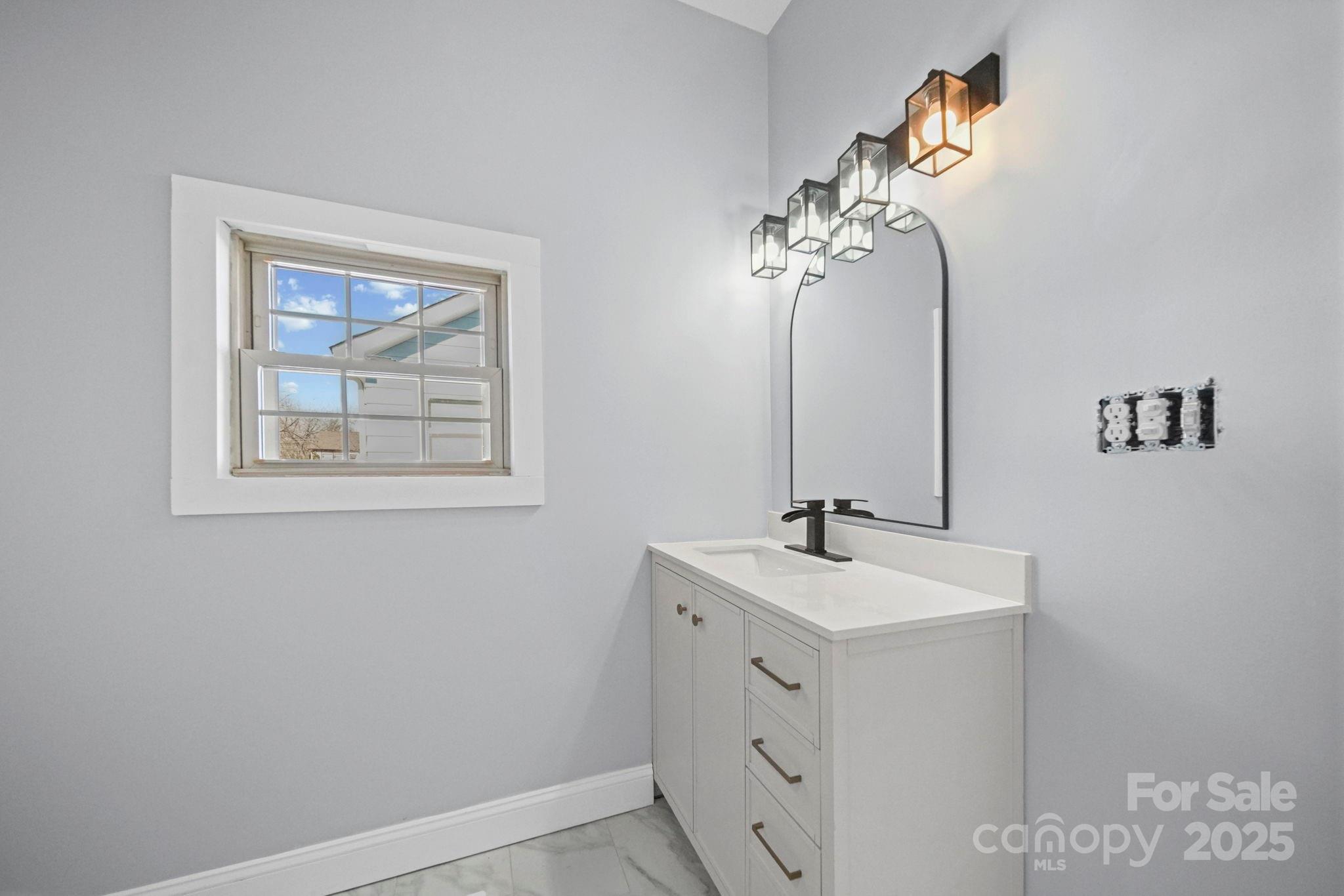 113 7th Street Spencer, NC 28159 - Photo 16 of 44 a bathroom with a sink a mirror and a painting on the wall