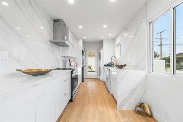 a kitchen with stainless steel appliances a refrigerator a sink a stove and white cabinets