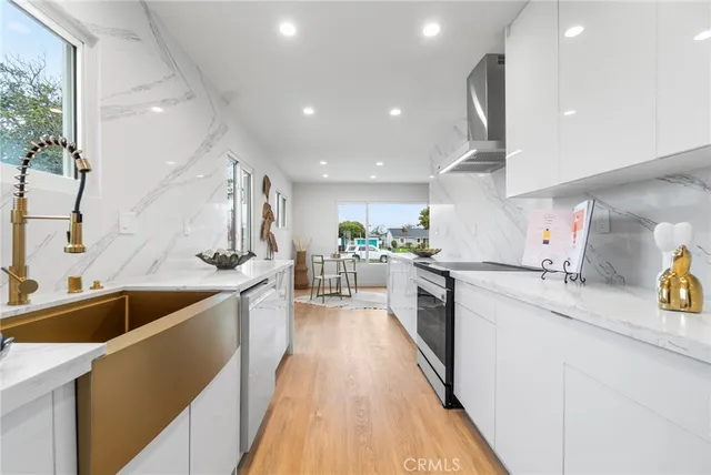 a kitchen with stainless steel appliances kitchen island granite countertop a sink a stove and a wooden floors