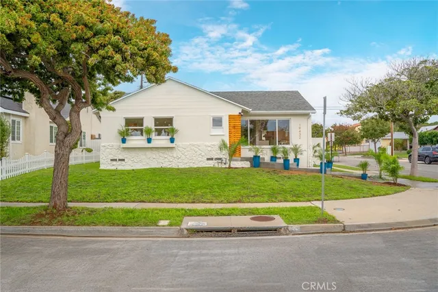 a front view of a house with a garden and trees