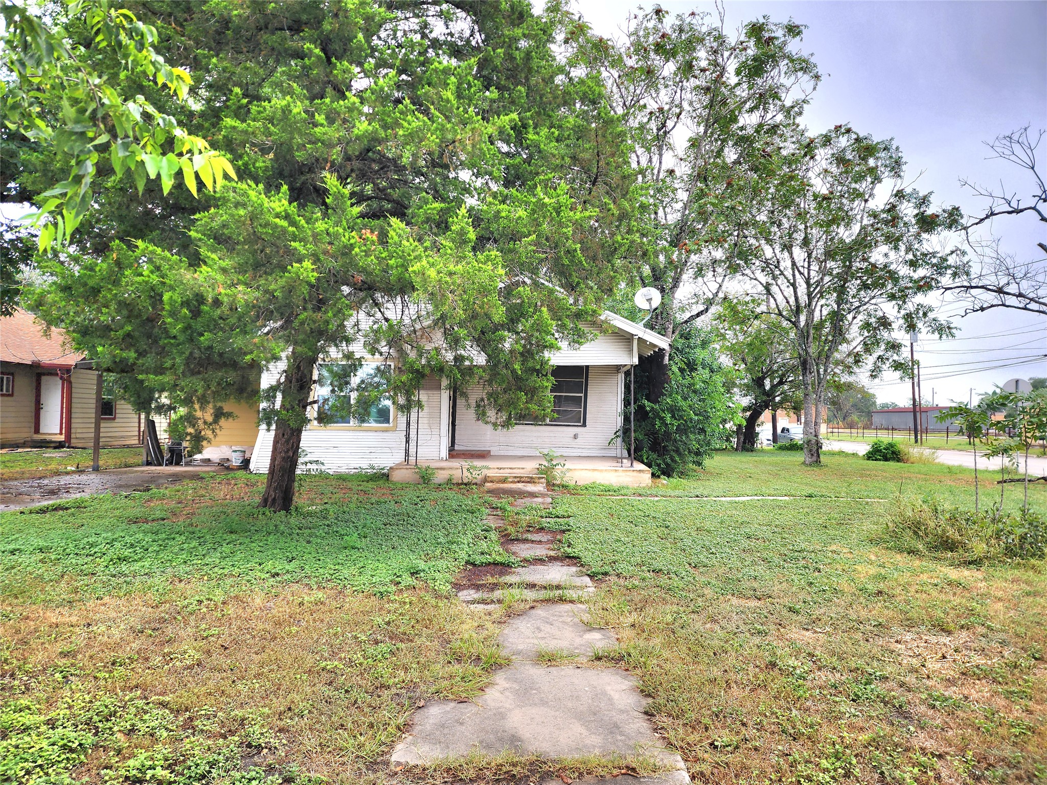 123 East Davis Street Luling, TX 78648 - Photo 4 of 14 A charming bungalow with a welcoming front path, nestled among mature trees.
