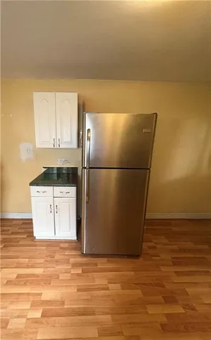 a view of a refrigerator in kitchen and empty room