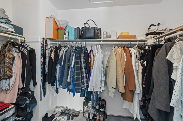 a view of walk in closet with clothes and shoes