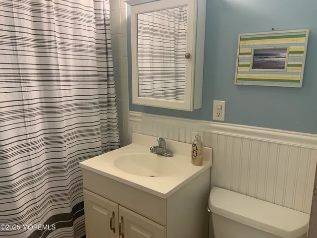 a bathroom with a sink a toilet and shower curtain