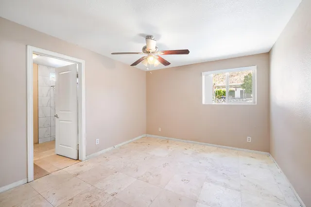 an empty room with windows and fan