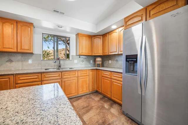 a kitchen with stainless steel appliances granite countertop a refrigerator a sink dishwasher a stove a dining table and chairs with wooden floor