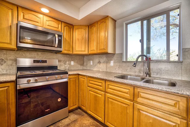a kitchen with stainless steel appliances granite countertop a stove a sink and a microwave