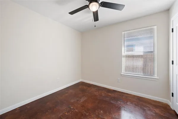 an empty room with a window and a ceiling fan