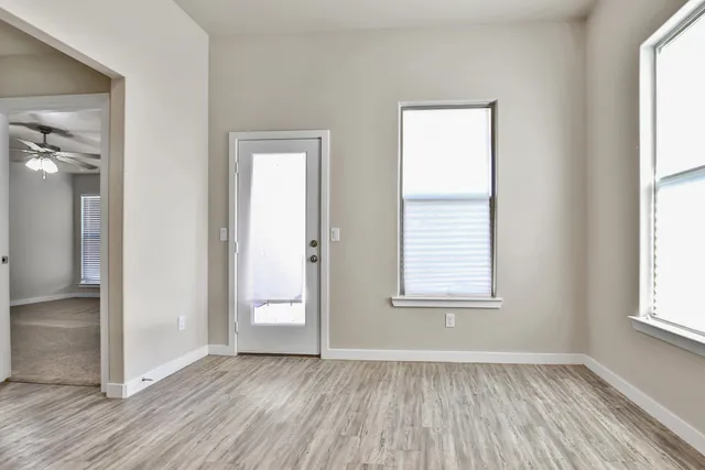 an empty room with wooden floor and windows