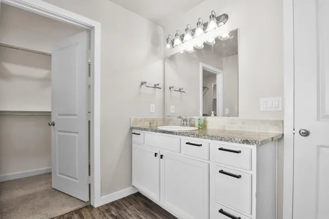 a bathroom with a granite countertop sink a large mirror and a shower