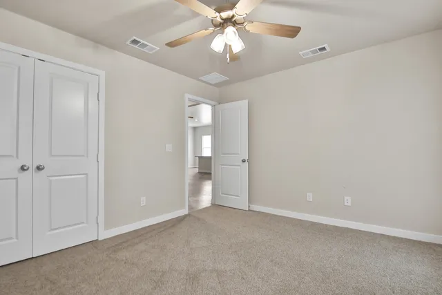 a view of an empty room and chandelier fan