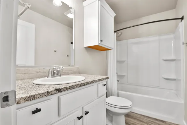 a bathroom with a granite countertop sink toilet and a mirror
