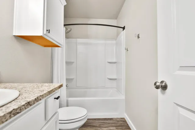 a bathroom with a granite countertop sink toilet and shower