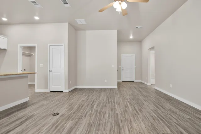 an empty room with wooden floor and windows