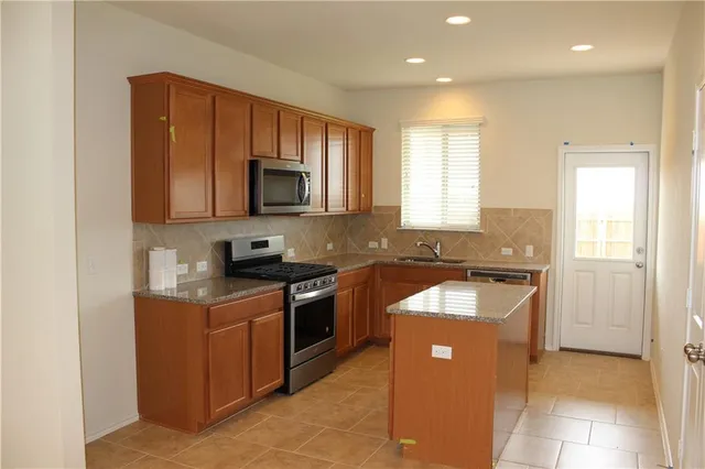 a kitchen with stainless steel appliances granite countertop a stove a sink and a microwave