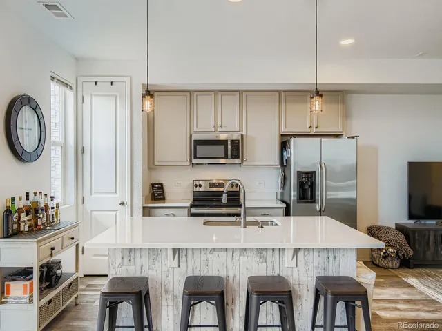 a kitchen with stainless steel appliances a table chairs refrigerator and microwave