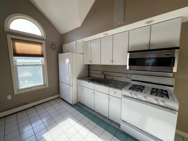 a kitchen with granite countertop white cabinets and white appliances