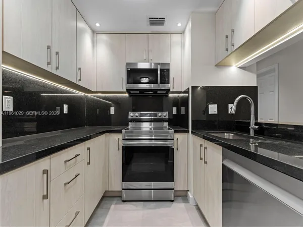 a kitchen with granite countertop a sink stainless steel appliances and cabinets