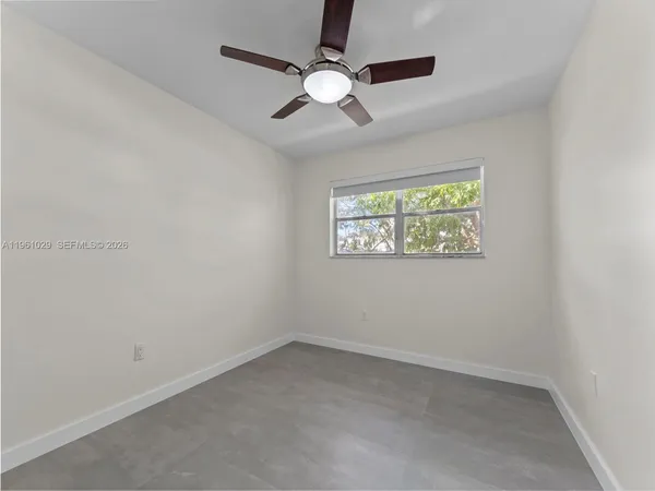 an empty room with a window and a fan