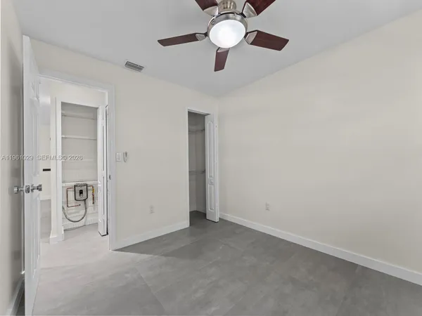an empty room with a chandelier fan and windows