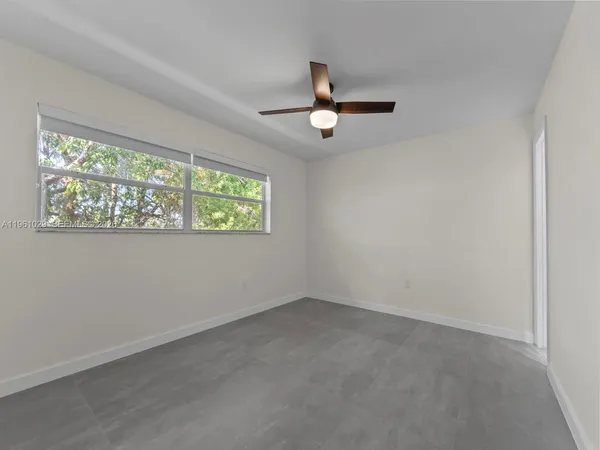 an empty room with windows and ceiling fan