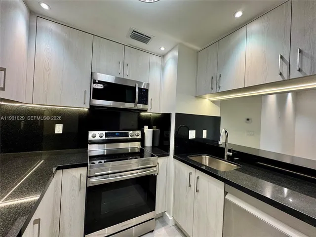 a kitchen with granite countertop a stove microwave and sink