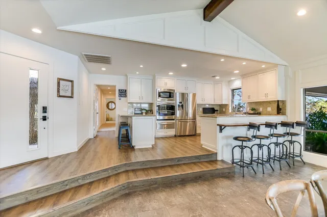 a spacious bedroom with a bed a dresser and wooden floor
