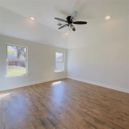 a view of an empty room with a window and wooden floor