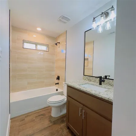 a bathroom with a granite countertop sink a toilet and bathtub