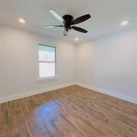 an empty room with wooden floor ceiling fan and windows