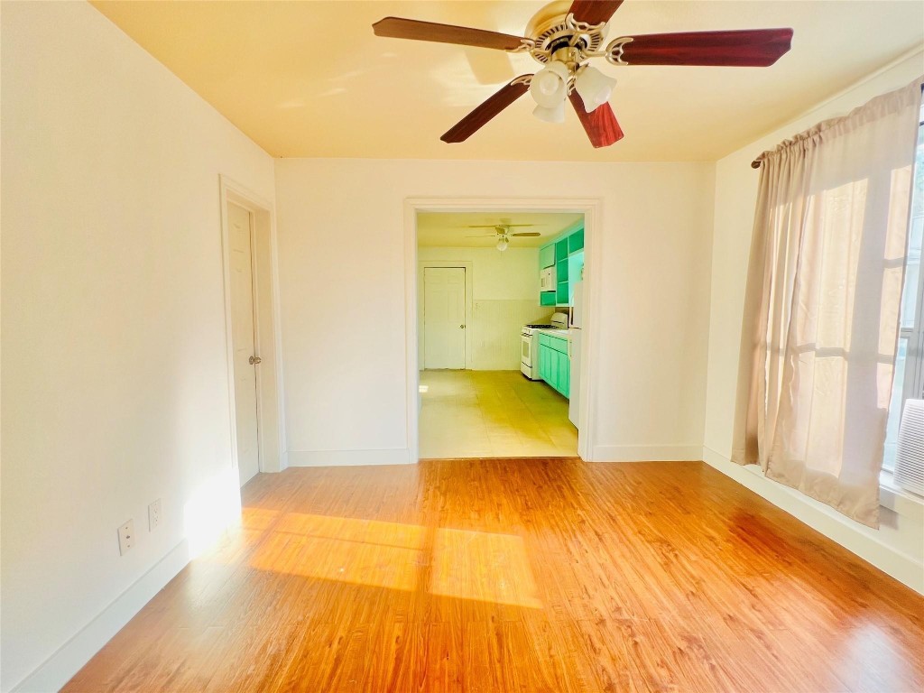 936 Bennington Street Houston, TX 77022 - Photo 4 of 12 a view of a big room with wooden floor a ceiling fan and windows