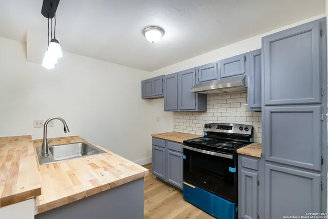 a kitchen with kitchen island granite countertop a refrigerator a stove and a sink with granite countertops