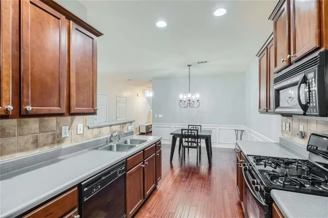 a kitchen with stainless steel appliances granite countertop a stove top oven a sink dishwasher a dining table and chairs with wooden floor