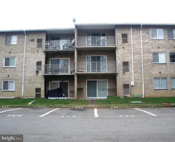 a front view of a building with a garden and parking space